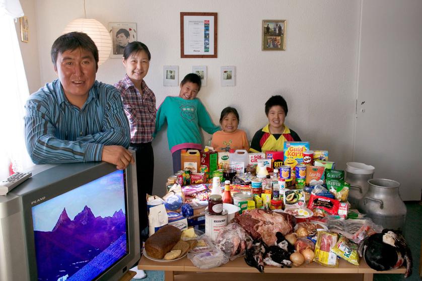 GRE04.0001.xxf1rw (MODEL RELEASED IMAGE) The Madsen family in their living room in Cap Hope village, Greenland, with a week’s worth of food. Standing by the TV are Emil Madsen, 40, and Erika Madsen, 26, with their children (left to right) Martin, 9, Belissa, 6, and Abraham, 12. Cooking method: gas stove. Food preservation: refrigerator-freezer. Favorite foods—Emil: polar bear. Erika: narwhal skin. Abraham and Belissa: Greenlandic food. Martin: Danish food. /// The Madsen family is one of the thirty families featured in the book Hungry Planet: What the World Eats (p. 144). Food expenditure for one week: $277.12 USD. (Since Emil is able to supplement his income guiding tourists around Greenland, the Madsens enjoy a fair amount of Danish food. For a more detailed look at the family’s food list Please refer to Hungry Planet book p. 145.)